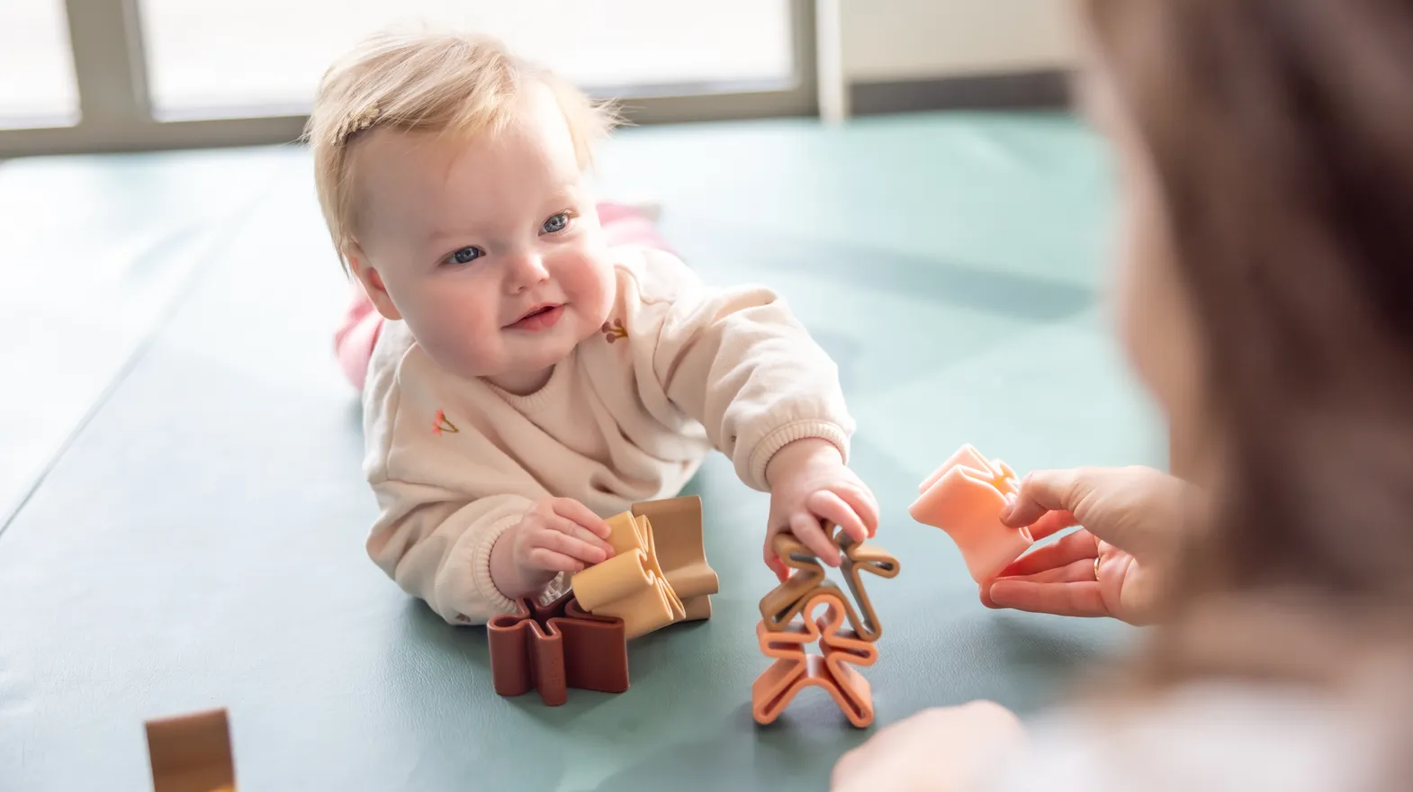Baby speelt met houten speelgoed poppetjes bij gastouder van kinderopvang Kind&co ludens