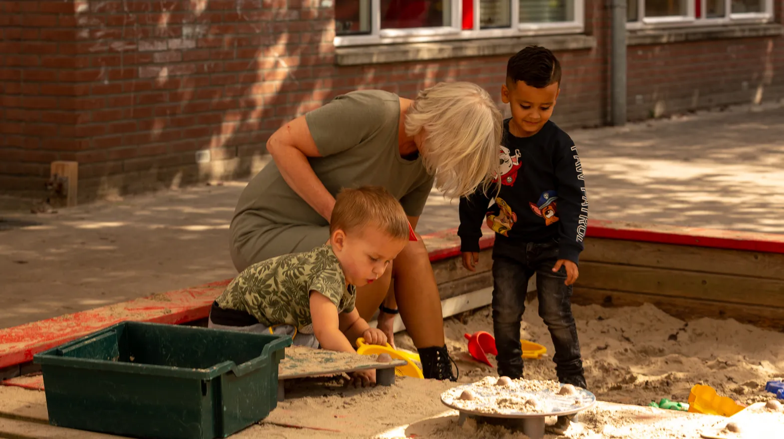 Kinderen spelen met pedagogisch medewerker in de zandbak bij Peuteropvang Het Margrietje Utrecht van kinderopvang Kind&co ludens