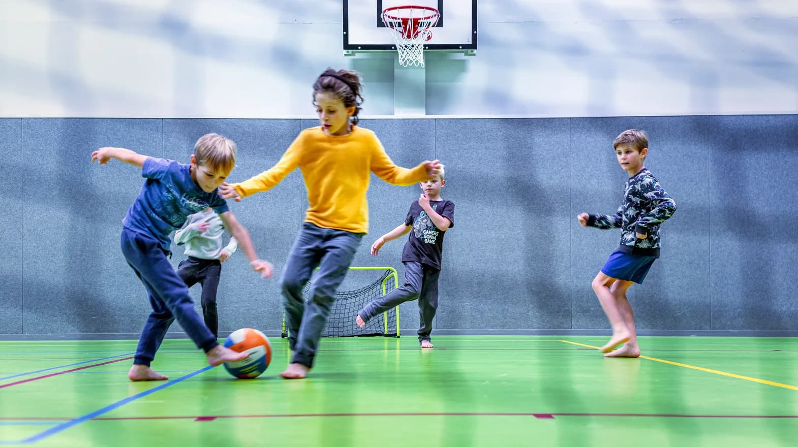 Kinderen van de BSO spelen samen voetbal in de gymzaal bij kinderopvang Kind&co ludens