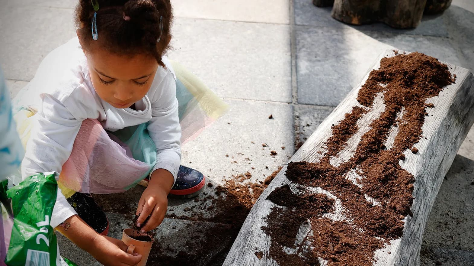 Kind van de peutergroep poot zaadjes in de moestuin bij kinderopvang Kind&co ludens