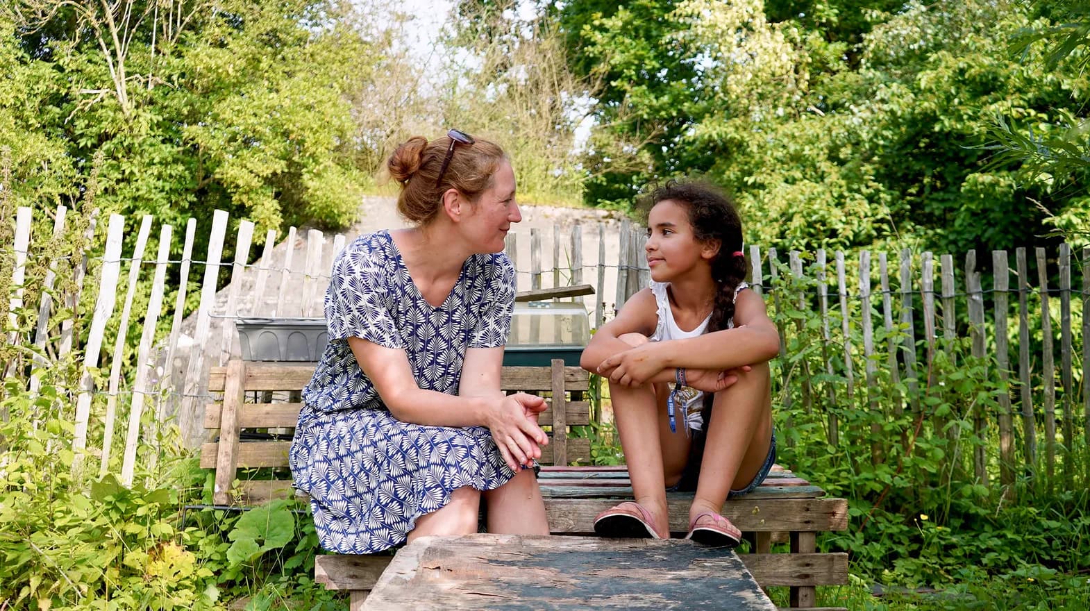 Kind bij de BSO praat buiten samen met de pedagogisch medewerker bij kinderopvang Kind&co ludens