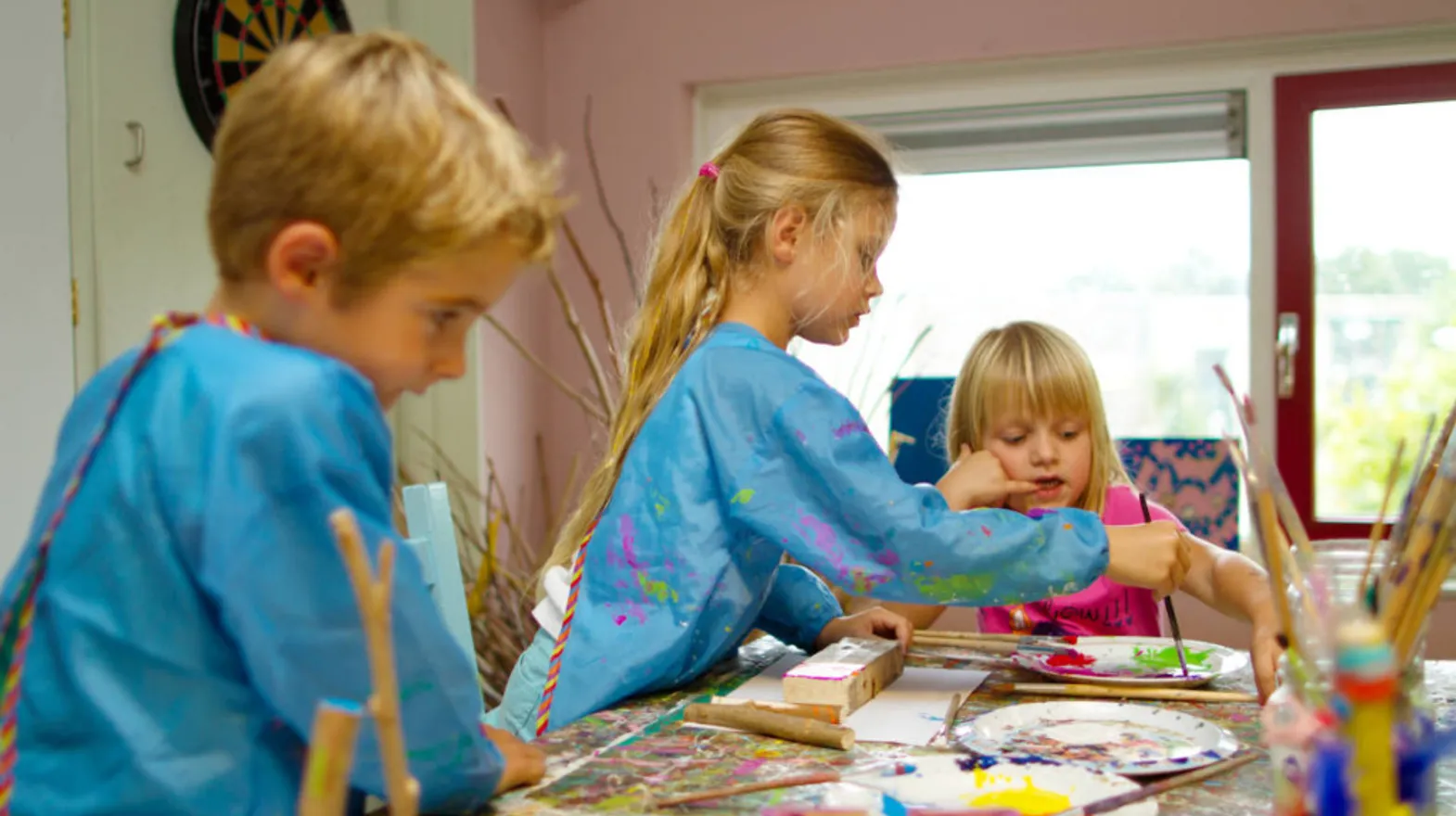 Kinderen verven aan een grote tafel bij buitenschoolse opvang Touwladder, kinderopvang Kind&co ludens