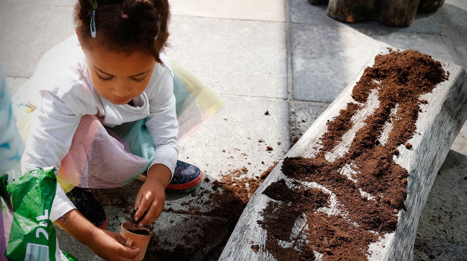 Kind van de peutergroep poot zaadjes in de moestuin bij kinderopvang Kind&co ludens