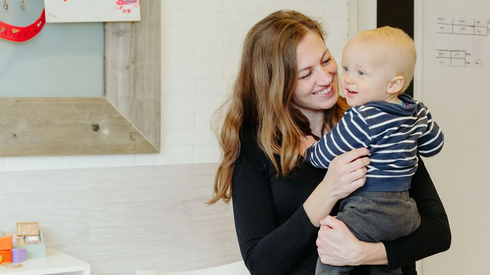 Pedagogisch medewerker knuffelt kind bij kinderdagverblijf De Tuinkabouter, kinderopvang Kind&co ludens