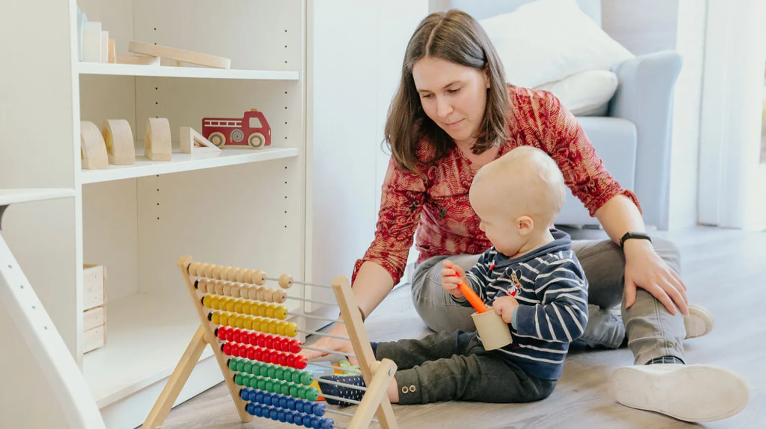 Pedagogisch medewerker speelt samen met kind met potjes en bekers bij kinderdagverblijf De Tuinkabouter, kinderopvang Kind&co ludens