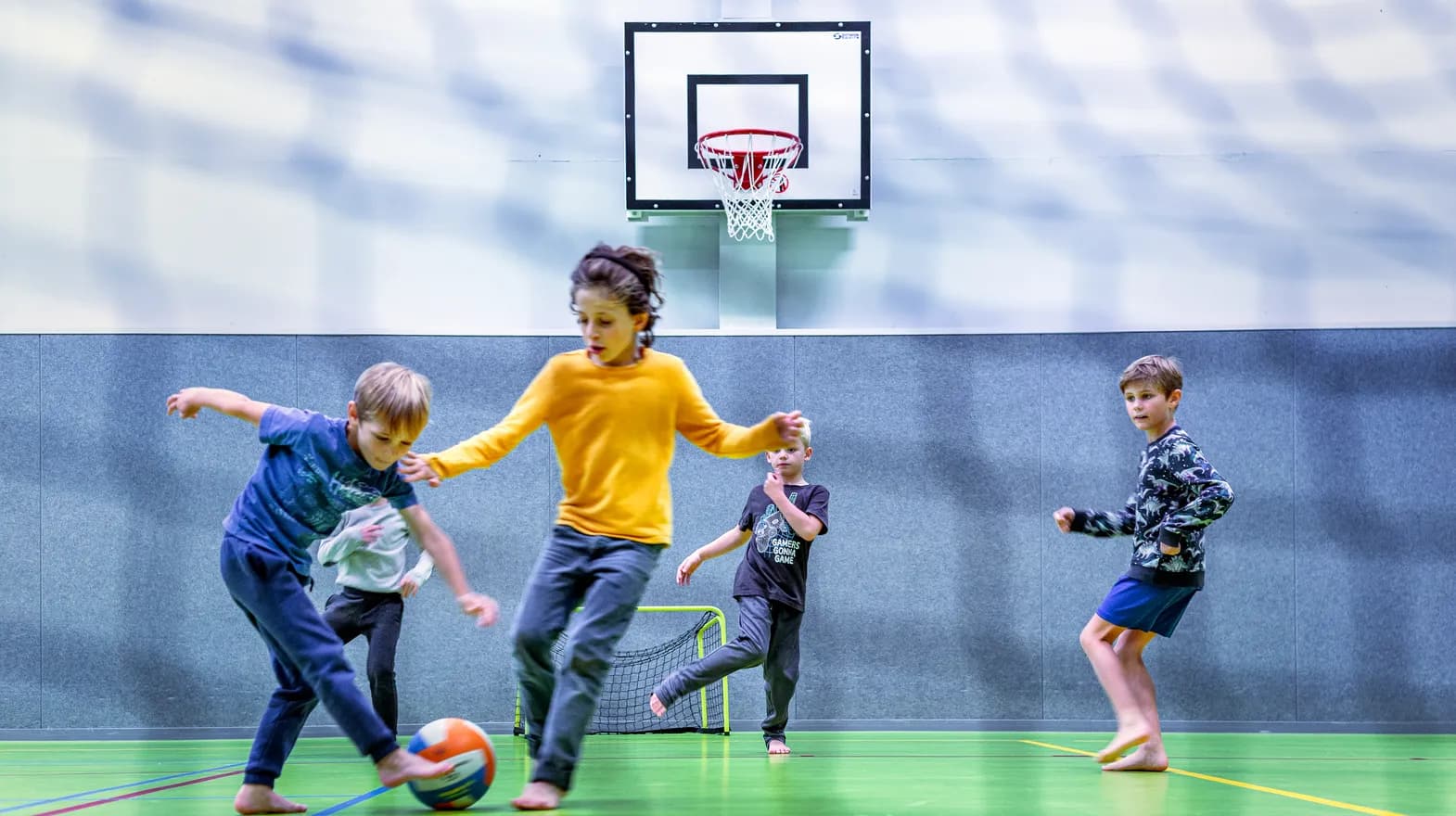 Kinderen van de BSO spelen samen voetbal in de gymzaal bij kinderopvang Kind&co ludens