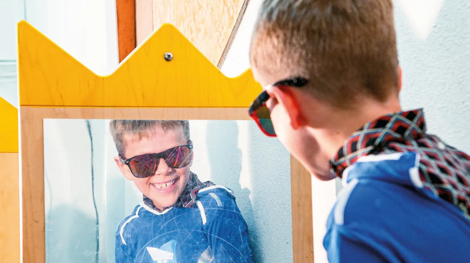 Kind op de BSO heeft veel plezier tijdens een verkleedpartij bij het kijken in de spiegel van kinderopvang Kind&co ludens