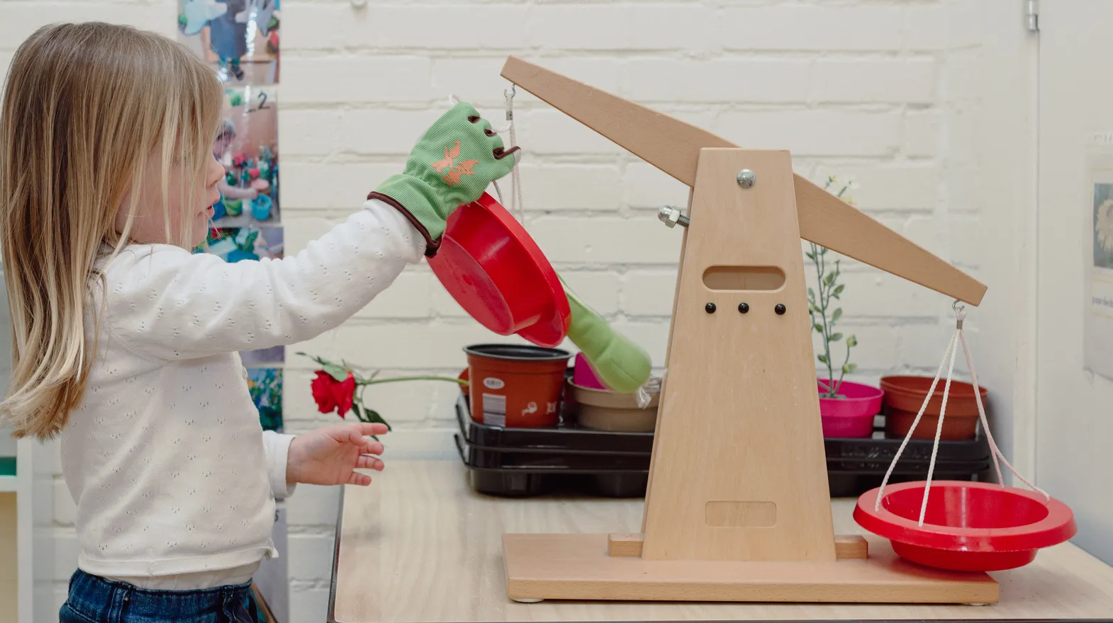 Een kind van de peutergroep speelt met een weegschaal bij kinderopvang Kind&co ludens