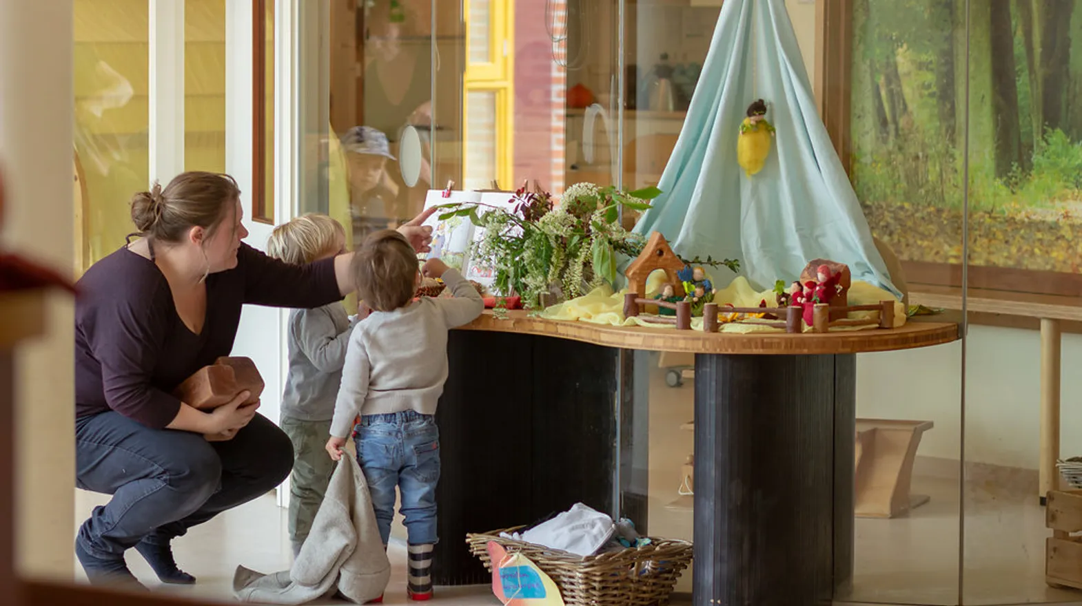 Kinderen kijken samen naar het boek en de stenen in de themahoek bij kinderdagverblijf Rozenrood, kinderopvang Kind&co ludens