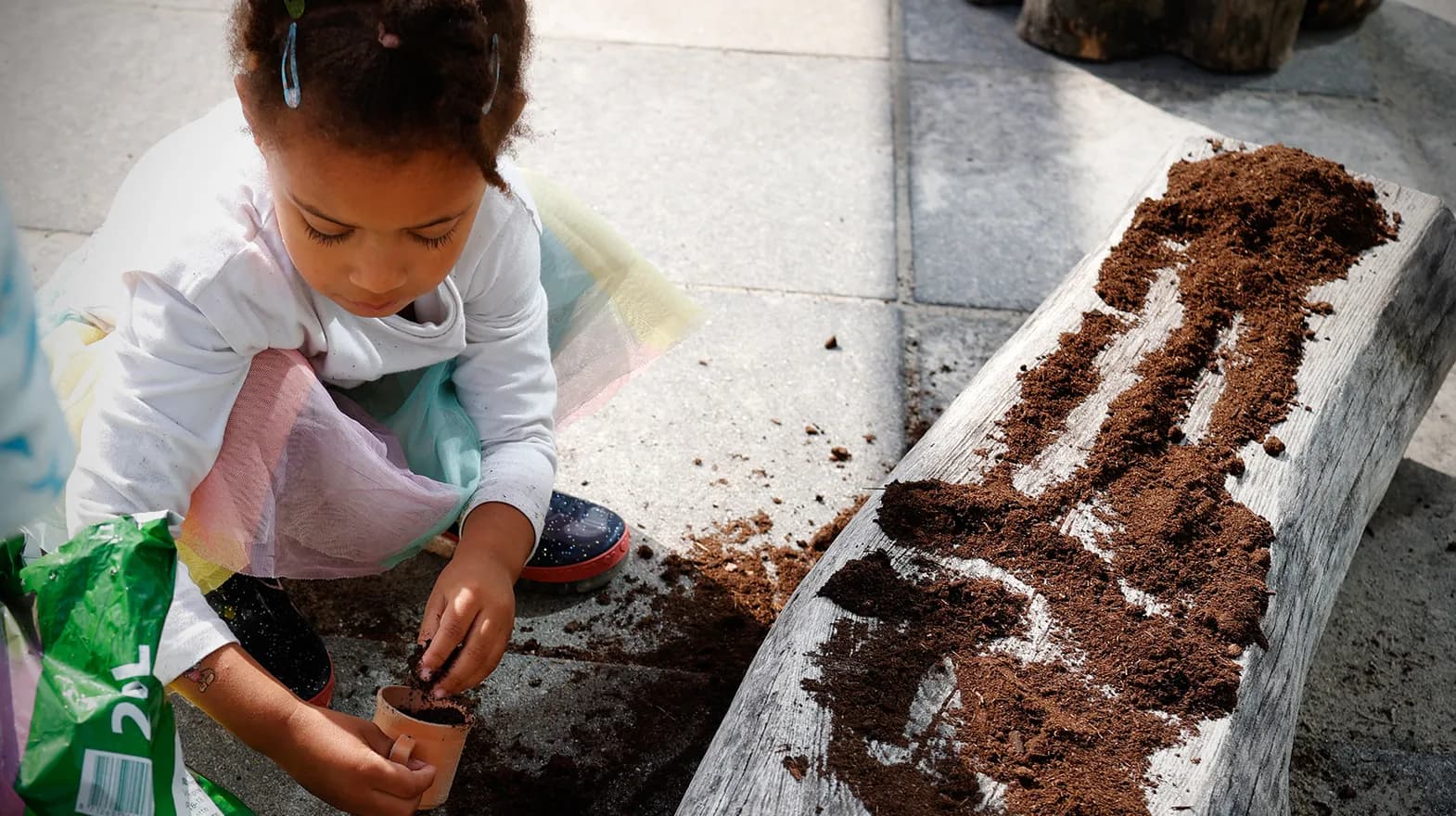 Kind van de peutergroep poot zaadjes in de moestuin bij kinderopvang Kind&co ludens