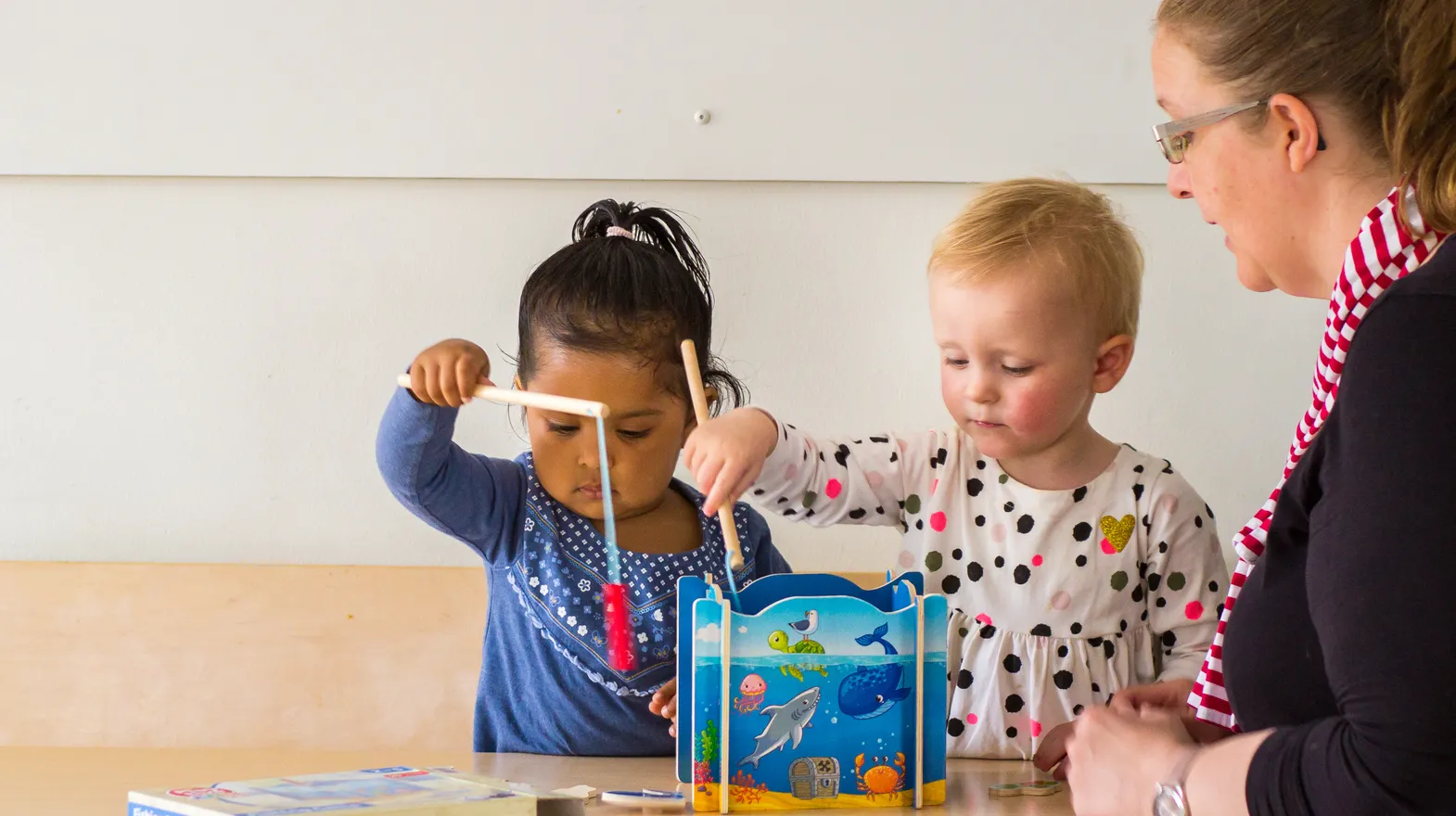 Kinderen spelen samen "Vissen" onder begeleiding van een pedagogisch medewerker bij kinderopvang Kind&co ludens