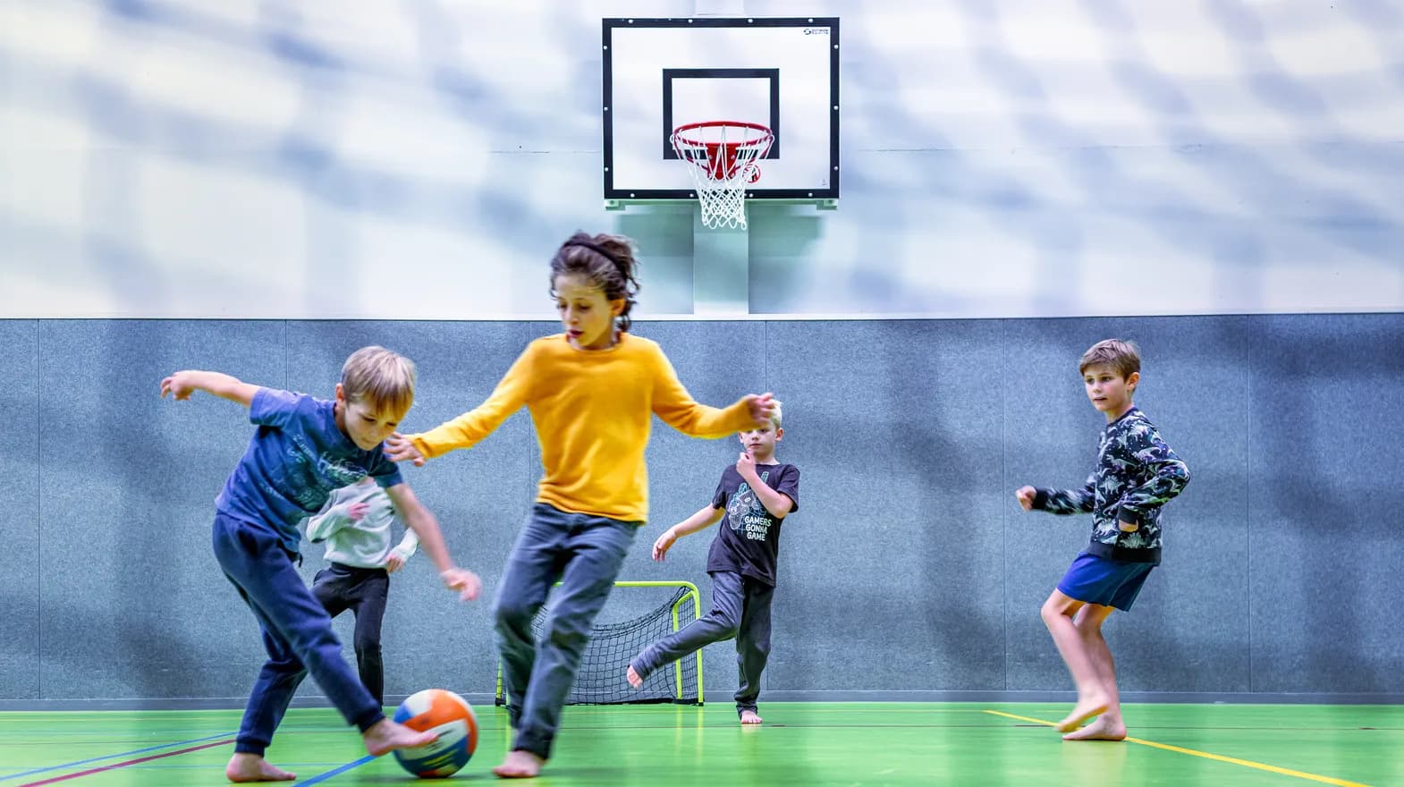 Kinderen van de BSO spelen samen voetbal in de gymzaal bij kinderopvang Kind&co ludens