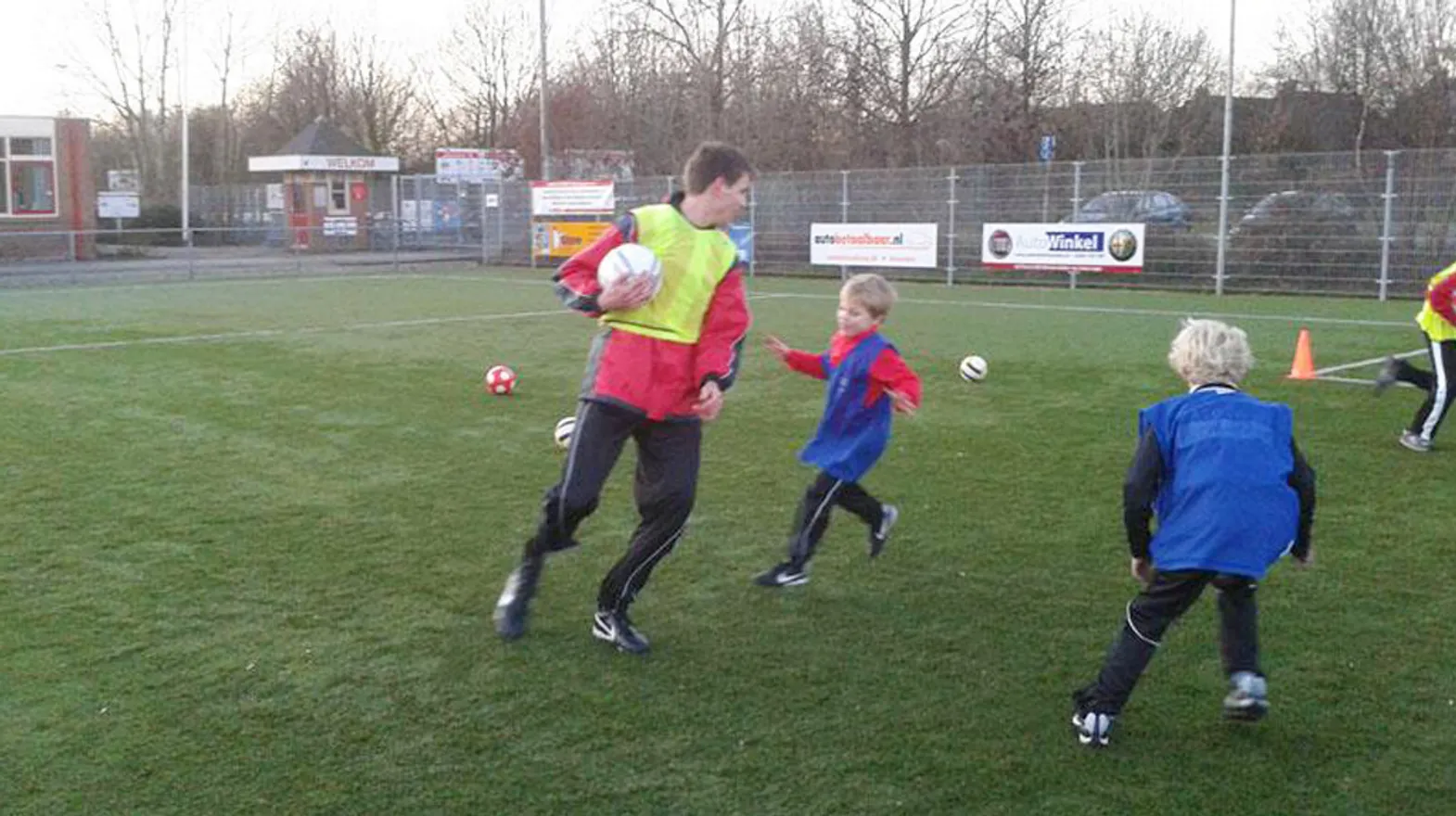 Kinderen samen met de Pedagogisch medewerker op het voetbalveld bij BSO Odijk Buitenspel van kinderopvang Kind&co ludens