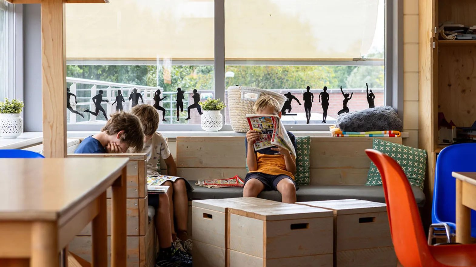 Kinderen lezen een stripboek in de chill-hoek bij buitenschoolse opvang Asterix en Obelix, kinderopvang Kind&co Ludens