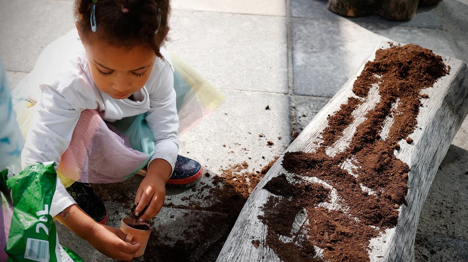 Kind van de peutergroep poot zaadjes in de moestuin bij kinderopvang Kind&co ludens