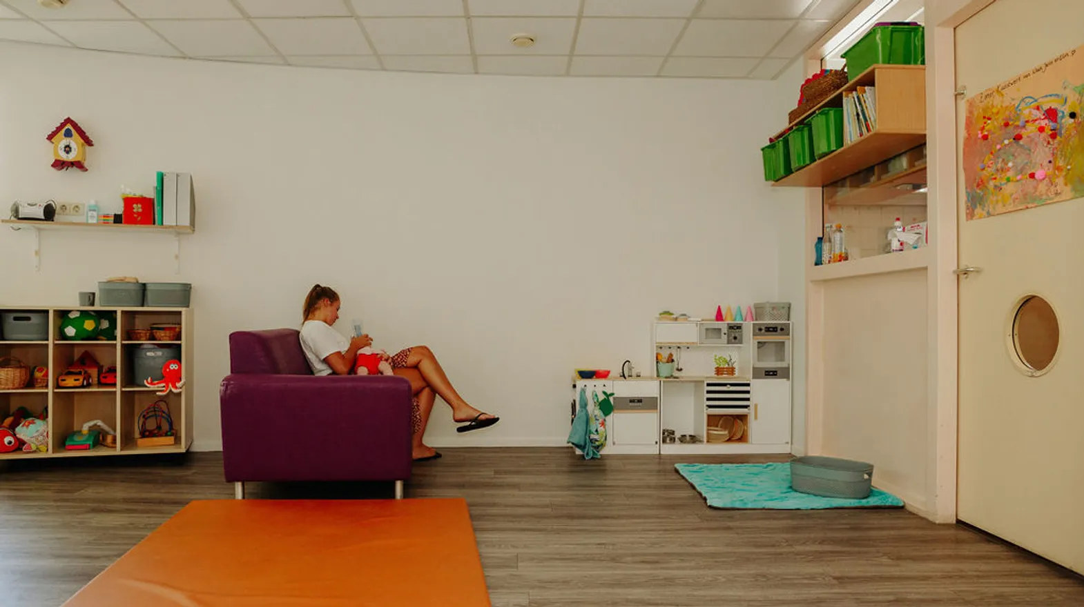 Pedagogisch medewerker geeft baby de fles bij kinderdagverblijf Jonas, kinderopvang Kind&co ludens