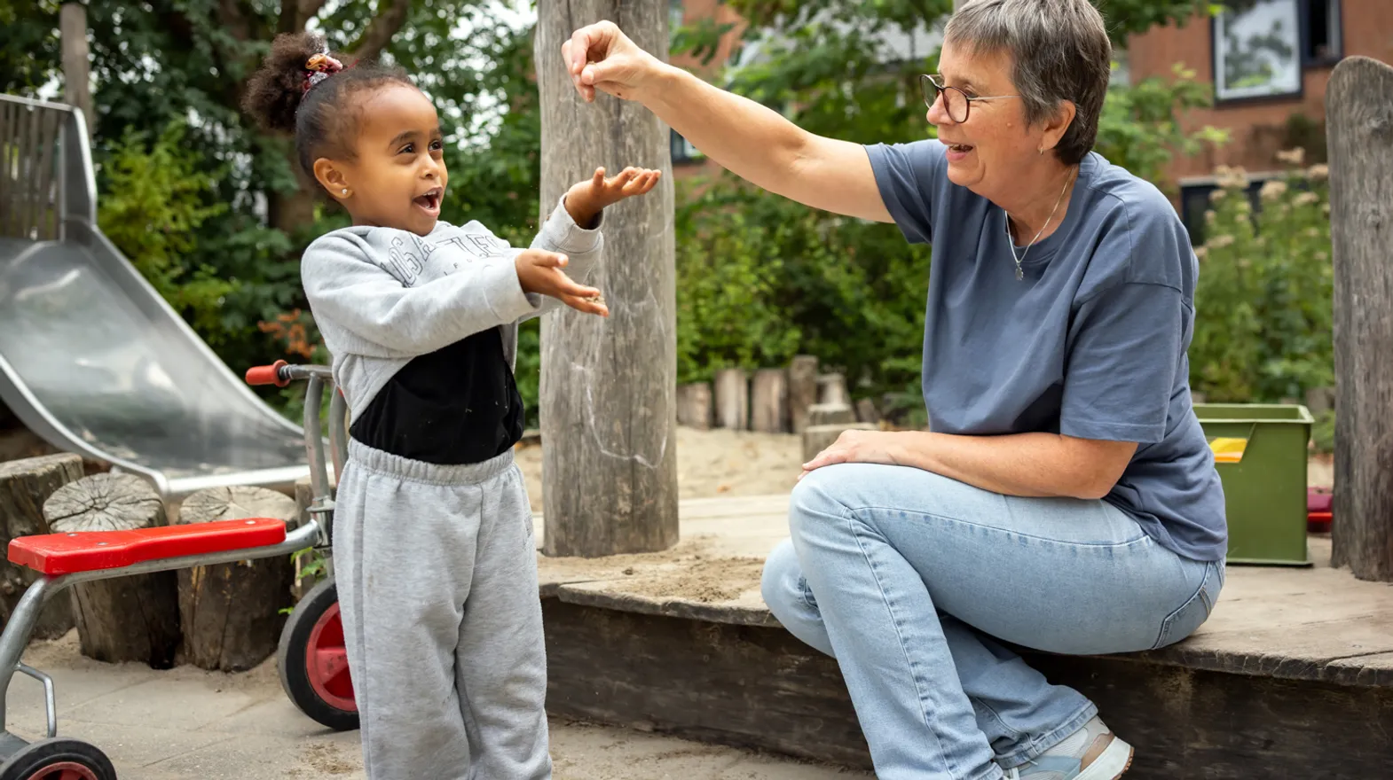 Kind speelt buiten met pedagogisch medewerker bij kinderopvang Kind&co ludens
