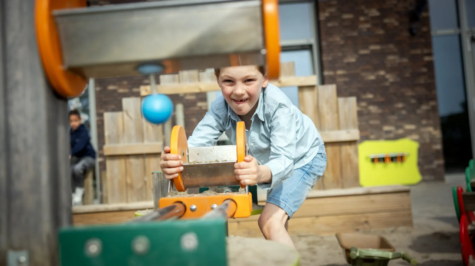 Kind speelt buiten met zand bij kinderopvang Kind&co ludens