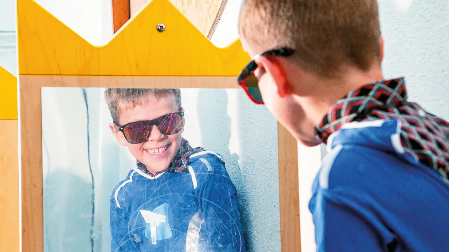 Kind op de BSO heeft veel plezier tijdens een verkleedpartij bij het kijken in de spiegel van kinderopvang Kind&co ludens