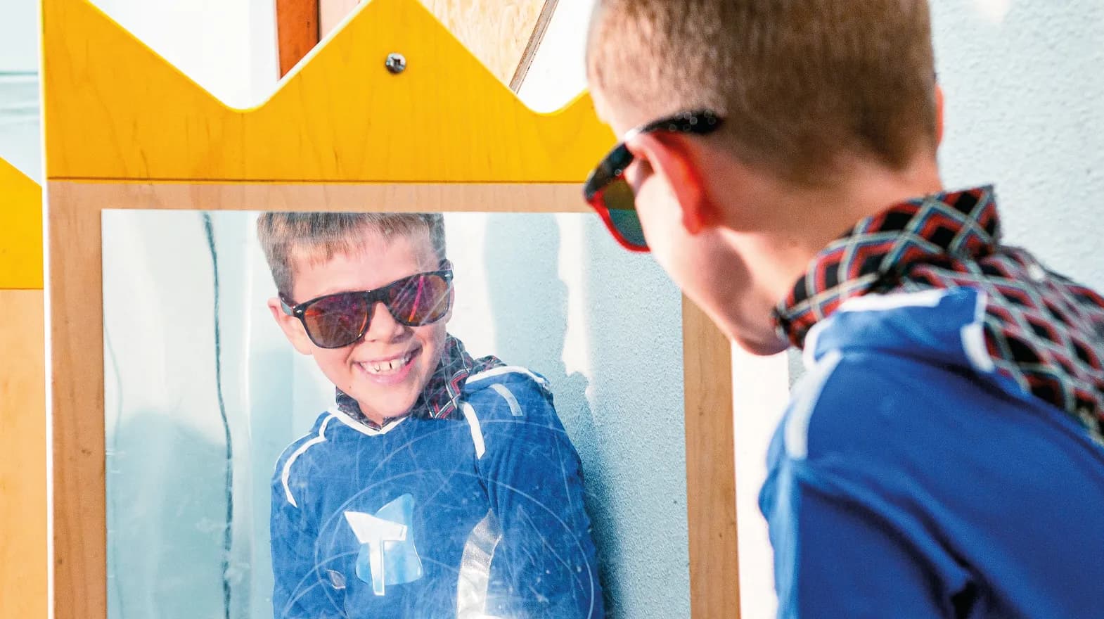 Kind op de BSO heeft veel plezier tijdens een verkleedpartij bij het kijken in de spiegel van kinderopvang Kind&co ludens