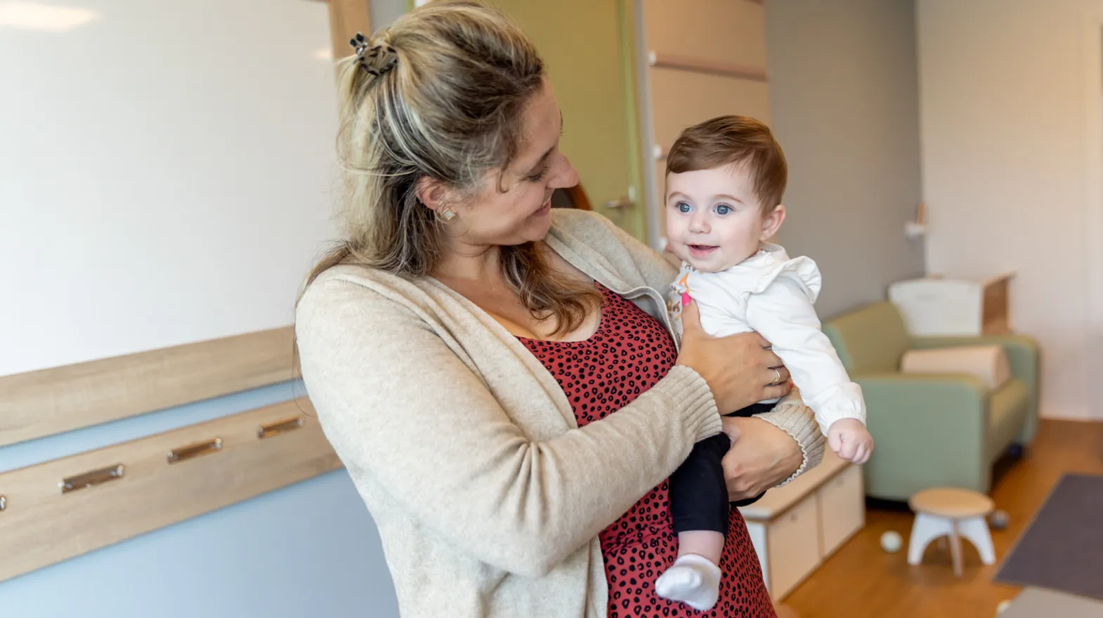 Baby wordt geknuffeld door pedagogisch medewerker bij kinderopvang Kind&co ludens