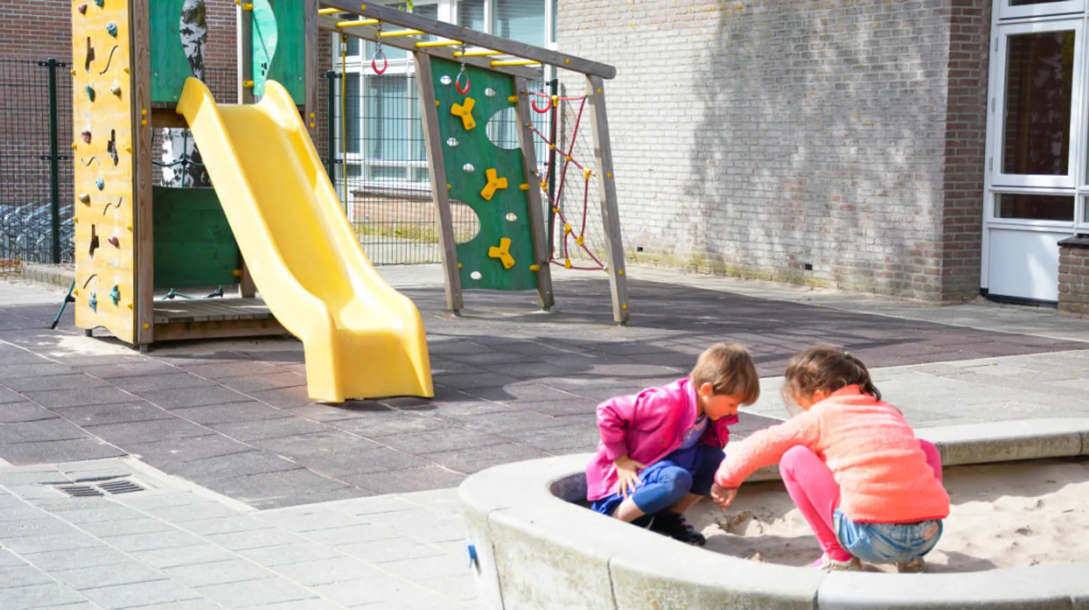 Kinderen spelen in zandbak met pedagogisch medewerker bij Kind&co ludens