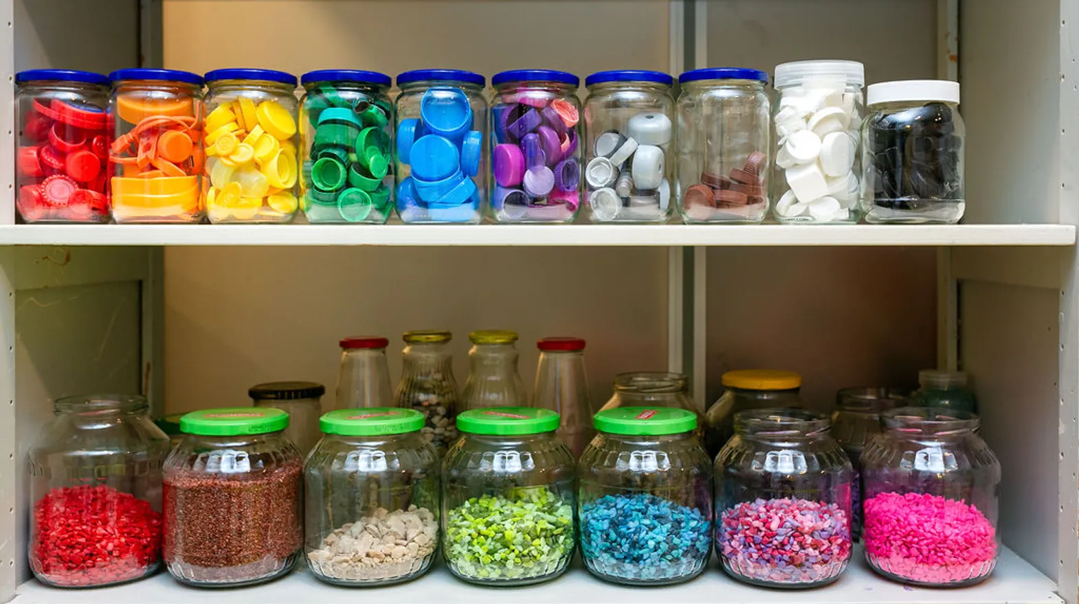 Potten vol met gekleurde steentjes en dopjes bij buitenschoolse opvang Odin, Kind&co Ludens