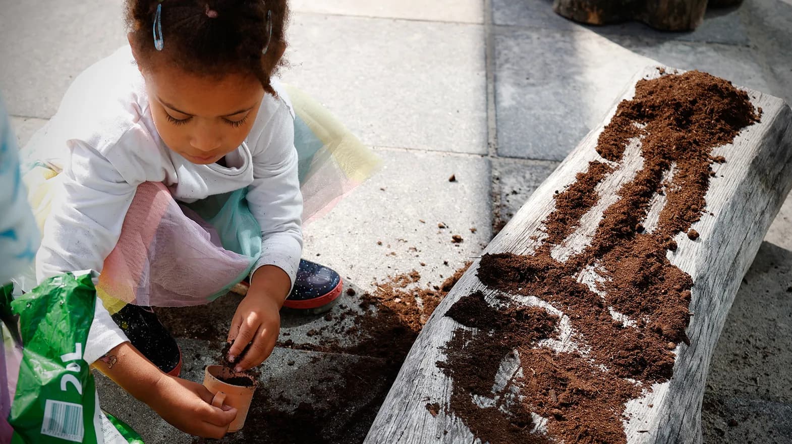 Kind van de peutergroep poot zaadjes in de moestuin bij kinderopvang Kind&co ludens