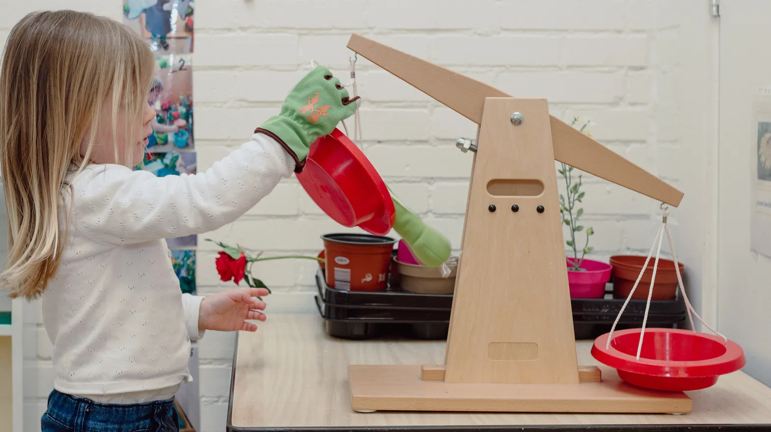 Een kind van de peutergroep speelt met een weegschaal bij kinderopvang Kind&co ludens