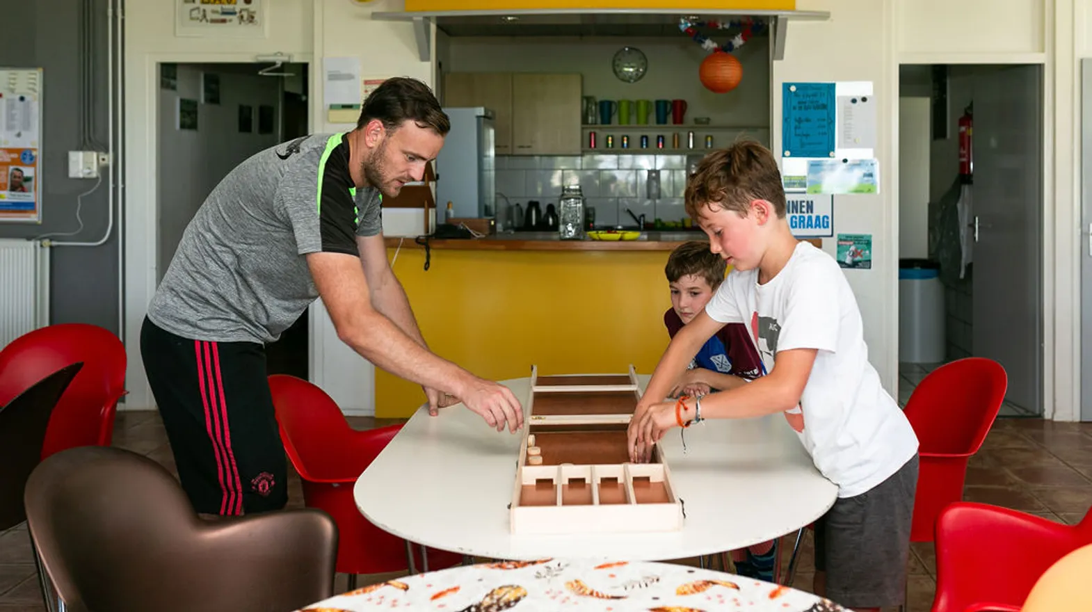 Kinderen aan het sjoelen in de groepsruimte bij BSO Sprint Baarn van kinderopvang Kind&co ludens