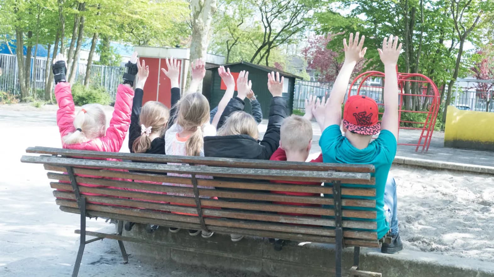 Kinderen juichen op een bankje buiten bij buitenschoolse opvang Knetterhonk, kinderopvang Kind&co Ludens