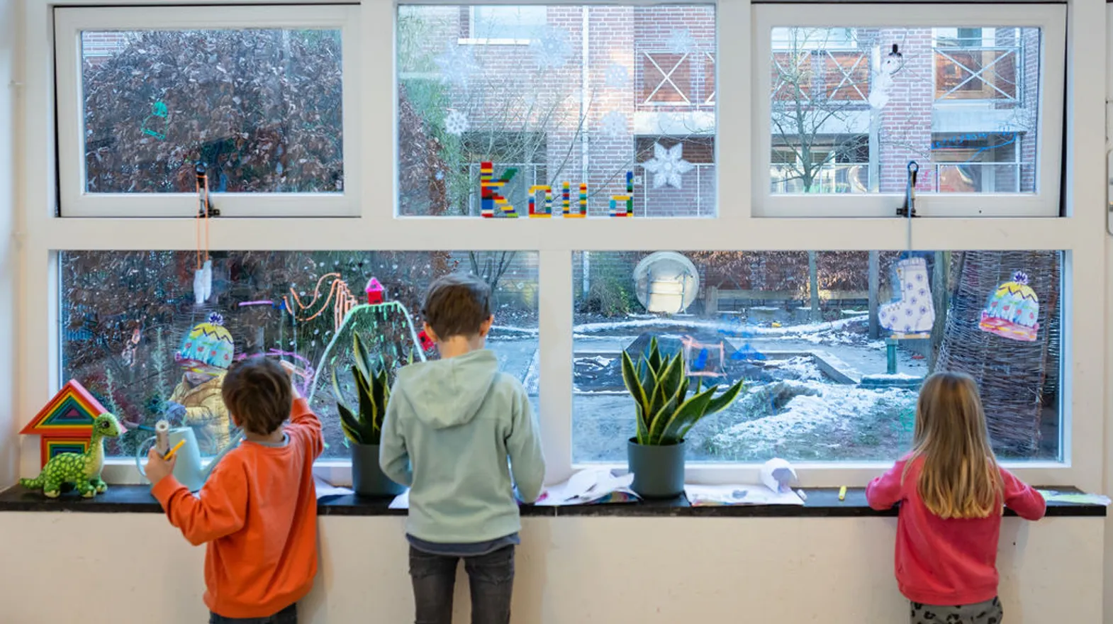 Kinderen schilderen op de ramen bij BSO Utrecht het Tuinhuis van kinderopvang Kind&co ludens