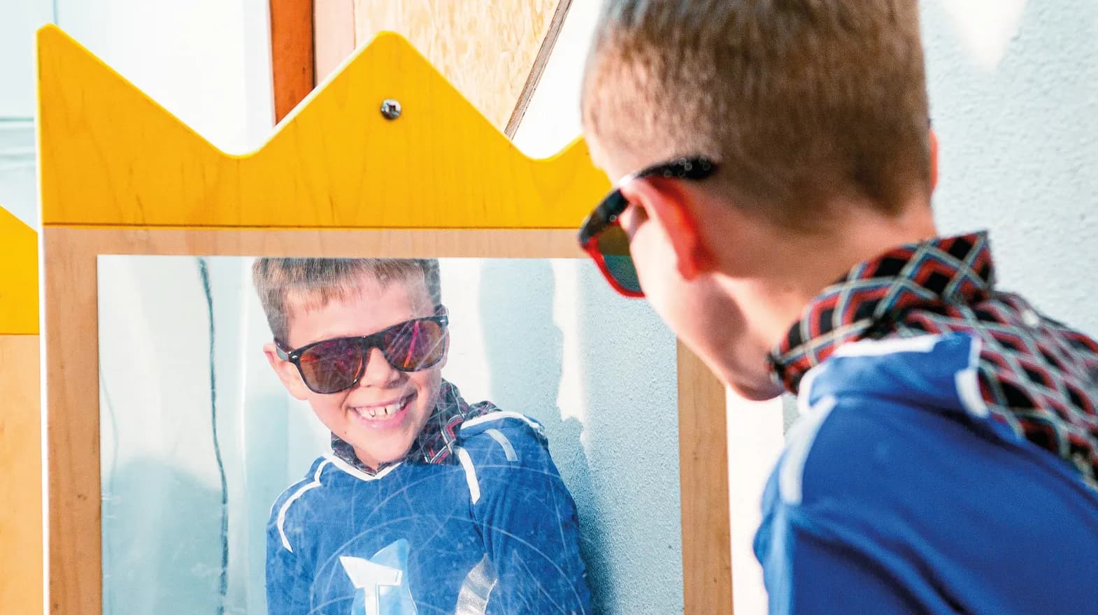 Kind op de BSO heeft veel plezier tijdens een verkleedpartij bij het kijken in de spiegel van kinderopvang Kind&co ludens