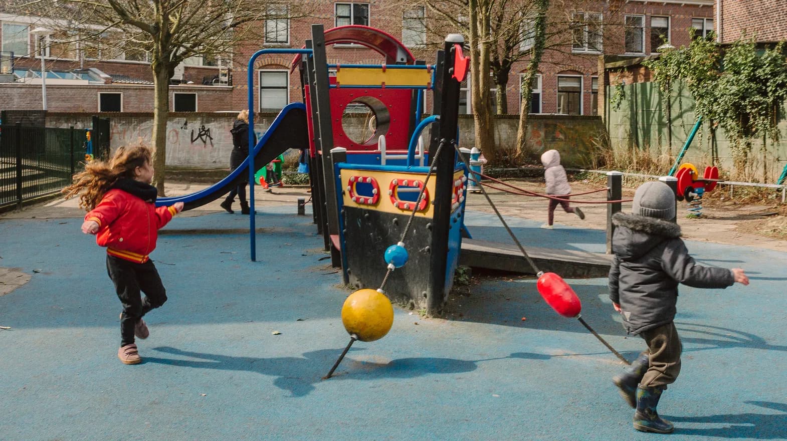 Kinderen spelen buiten met een speeltoestel bij kinderopvang Kind&co ludens