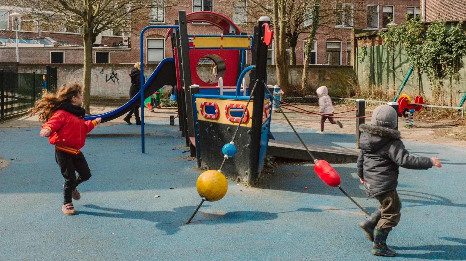 Kinderen spelen buiten met een speeltoestel bij kinderopvang Kind&co ludens