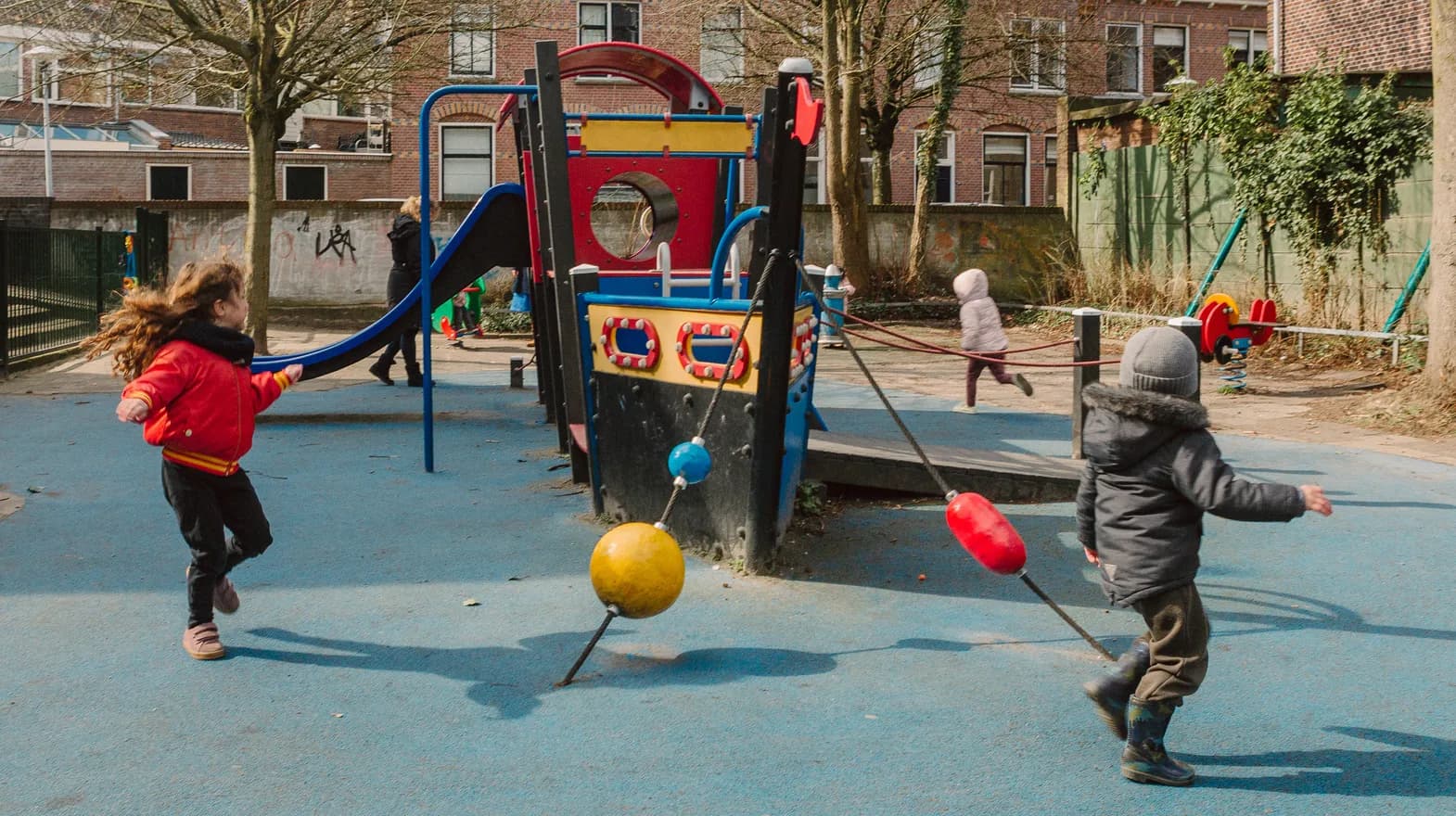 Kinderen spelen buiten met een speeltoestel bij kinderopvang Kind&co ludens