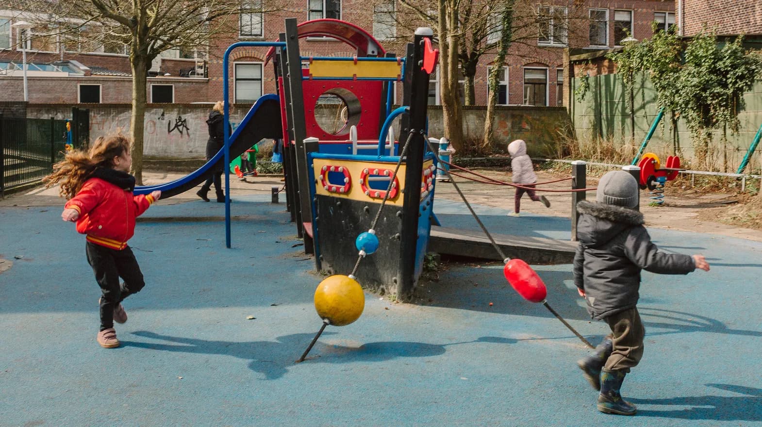Kinderen spelen buiten met een speeltoestel bij kinderopvang Kind&co ludens