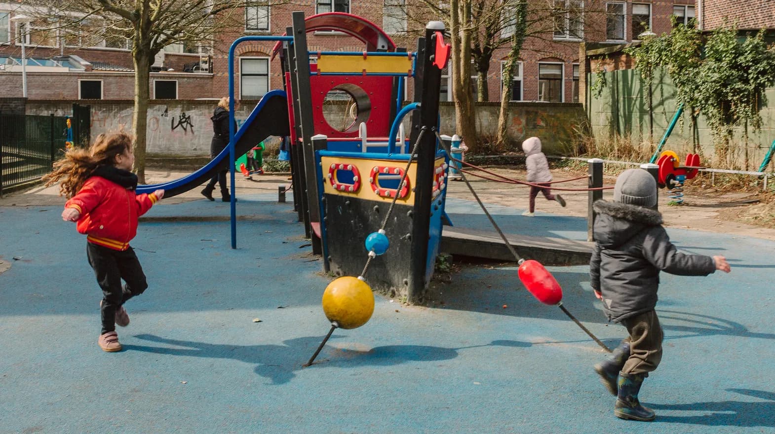 Kinderen spelen buiten met een speeltoestel bij kinderopvang Kind&co ludens