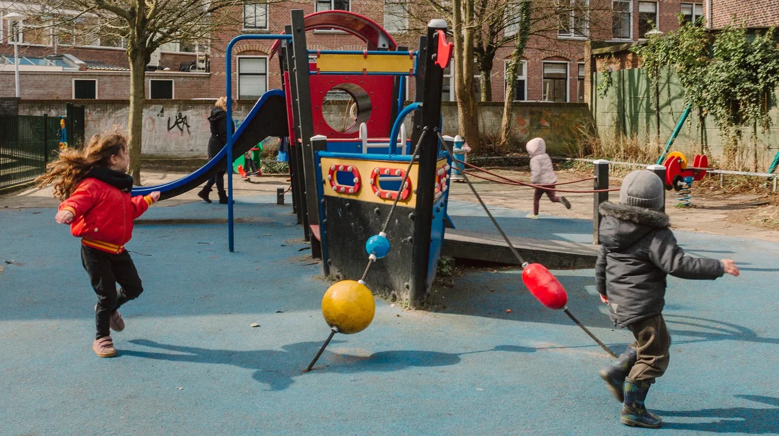 Kinderen spelen buiten met een speeltoestel bij kinderopvang Kind&co ludens