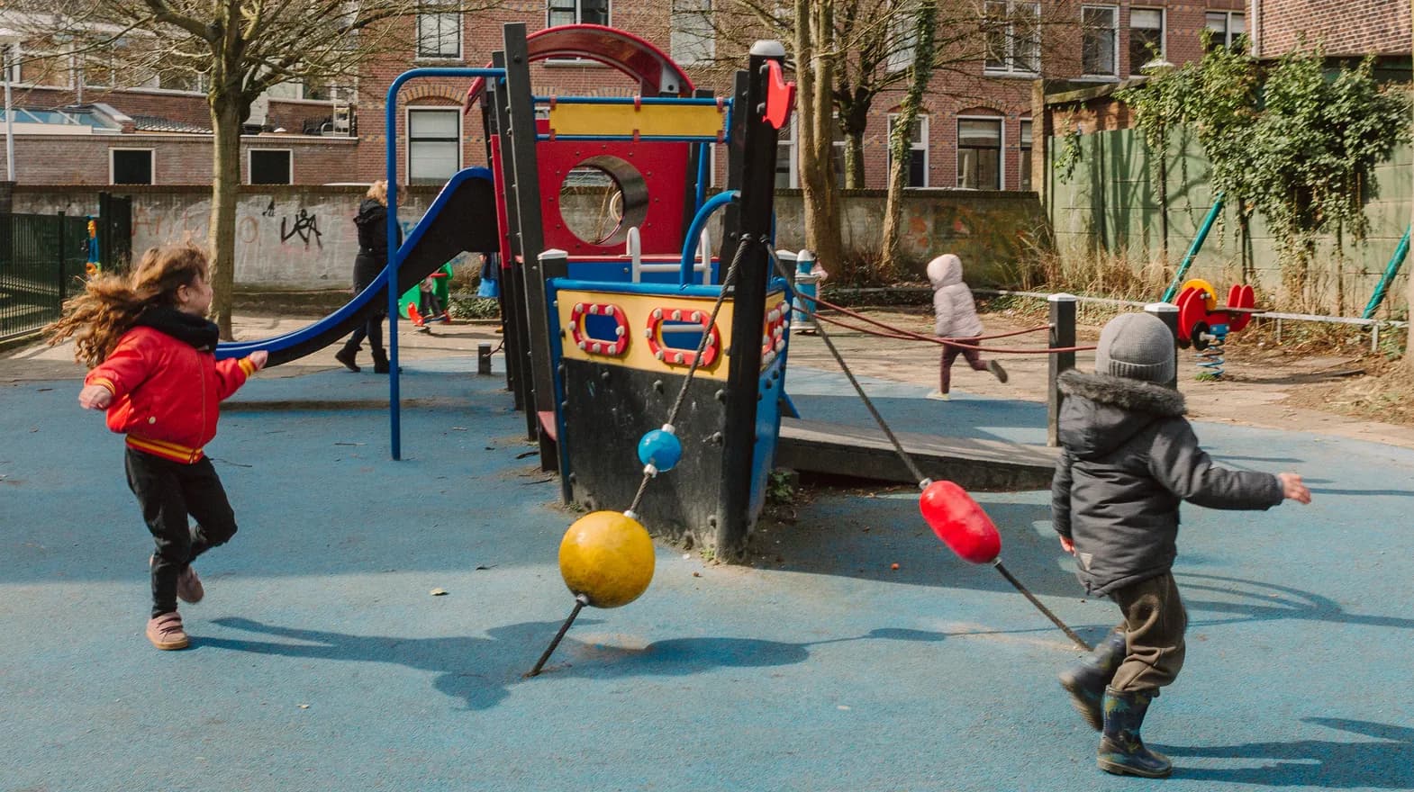 Kinderen spelen buiten met een speeltoestel bij kinderopvang Kind&co ludens