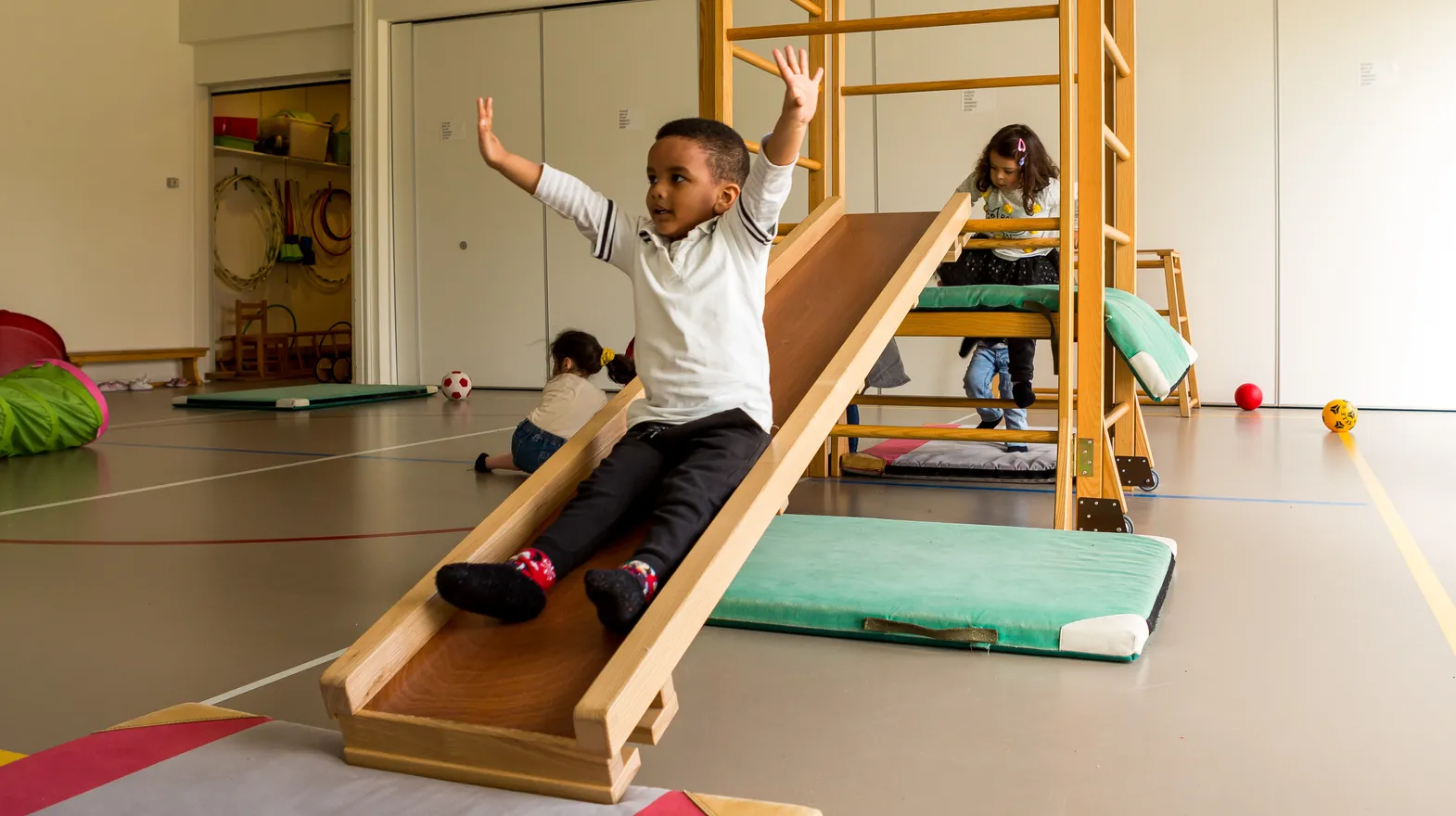 Kinderen klimmen en glijden in gymzaal bij kinderopvang Kind&co ludens