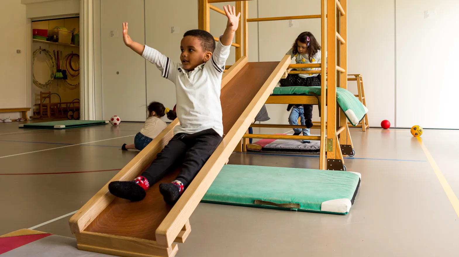 Kinderen klimmen en glijden in gymzaal bij kinderopvang Kind&co ludens