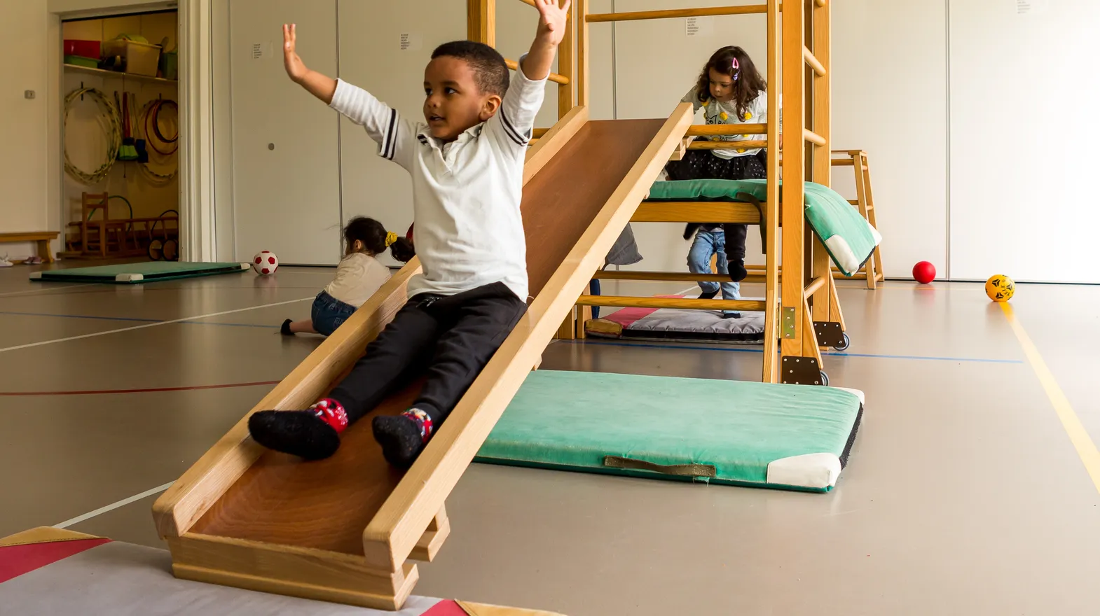 Kinderen klimmen en glijden in gymzaal bij kinderopvang Kind&co ludens