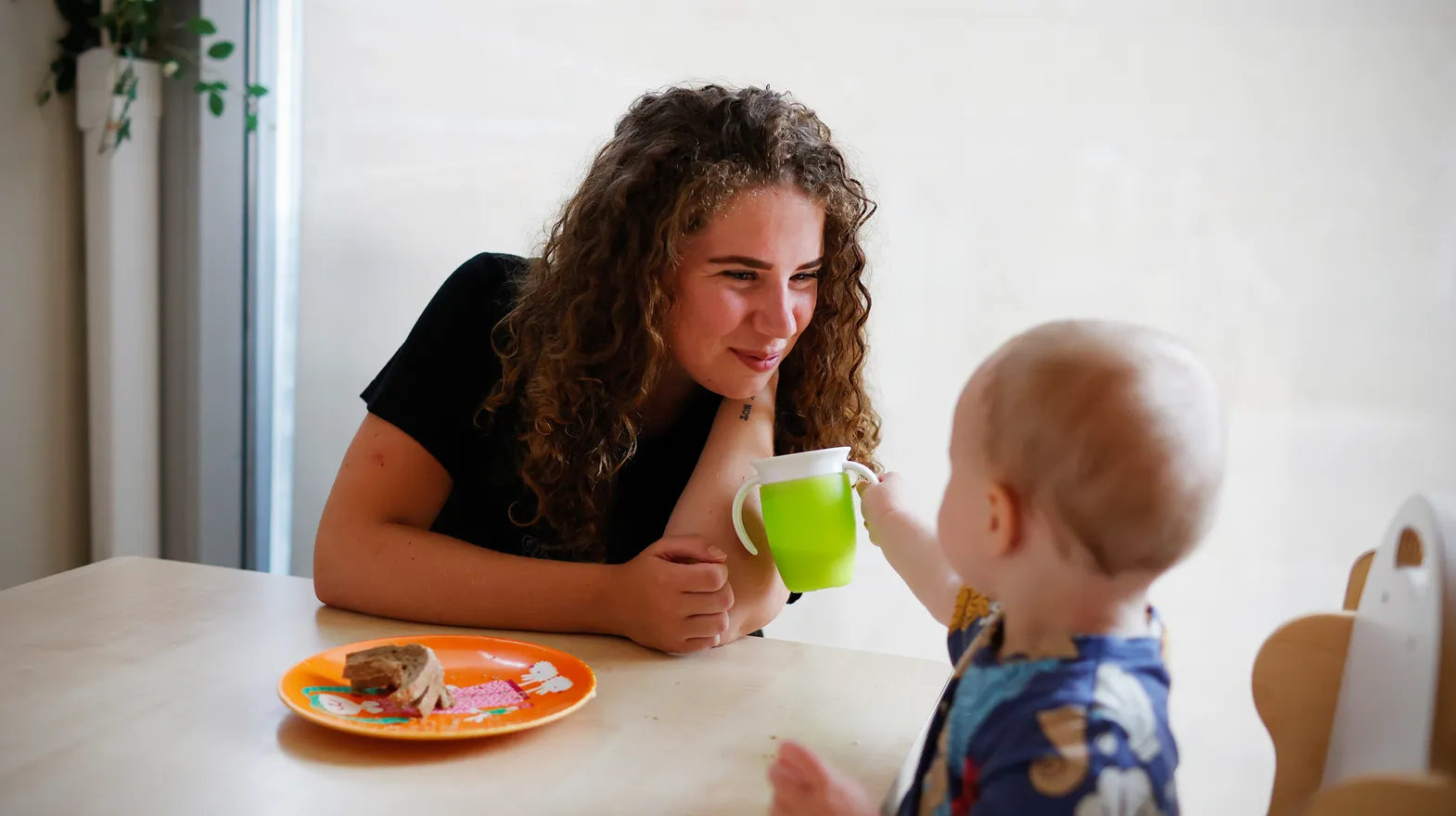 Kind eet samen met pedagogisch medewerker bij kinderopvang Kind&co ludens