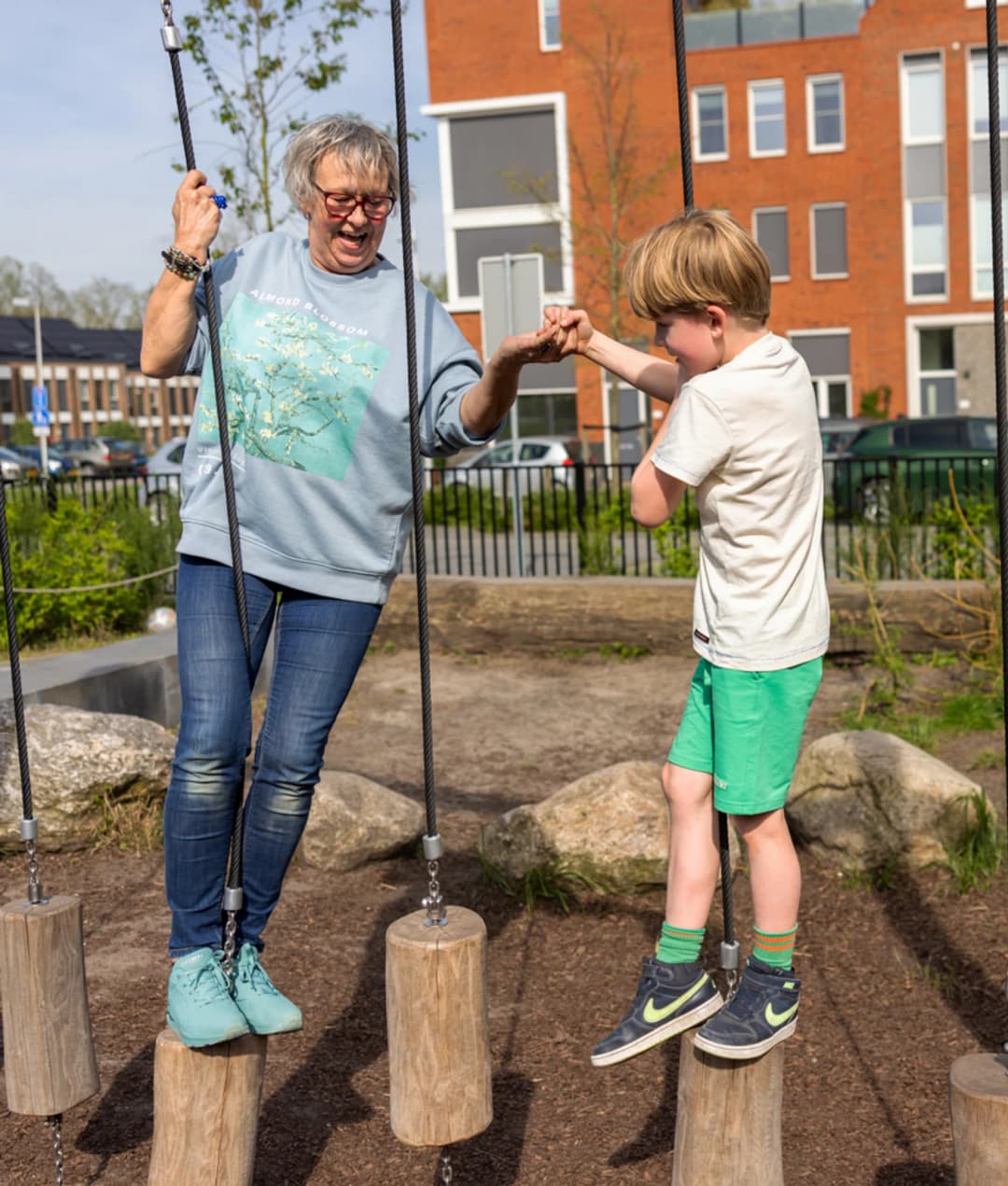 Kind en pedagogisch medewerker spelen buiten op balansblokken bij kinderopvang Kind&co ludens