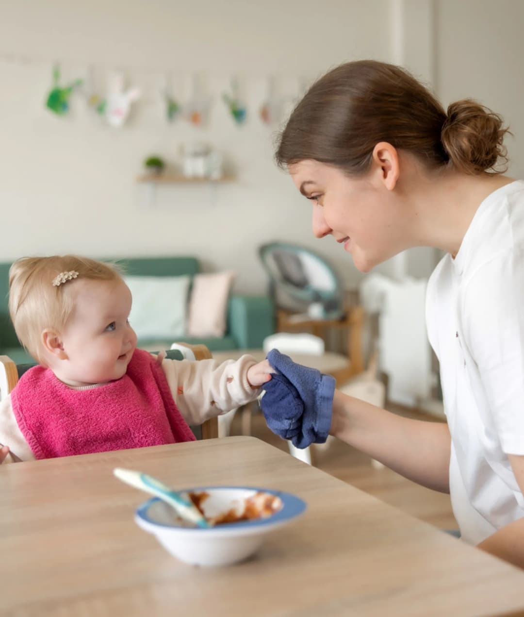 kindje wordt geholpen bij het eten door een pedagogisch medewerker bij kinderopvang Kind&co ludens