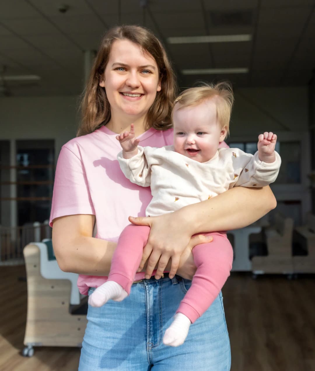 Blij kind op de armen bij een pedagogisch medewerker bij kinderopvang Kind&co ludens