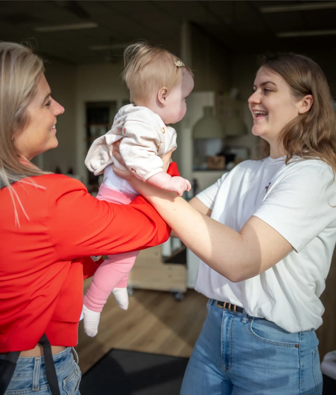 Baby wordt door de moeder aan de pedagogisch medewerker gegeven bij kinderopvang Kind&co ludens