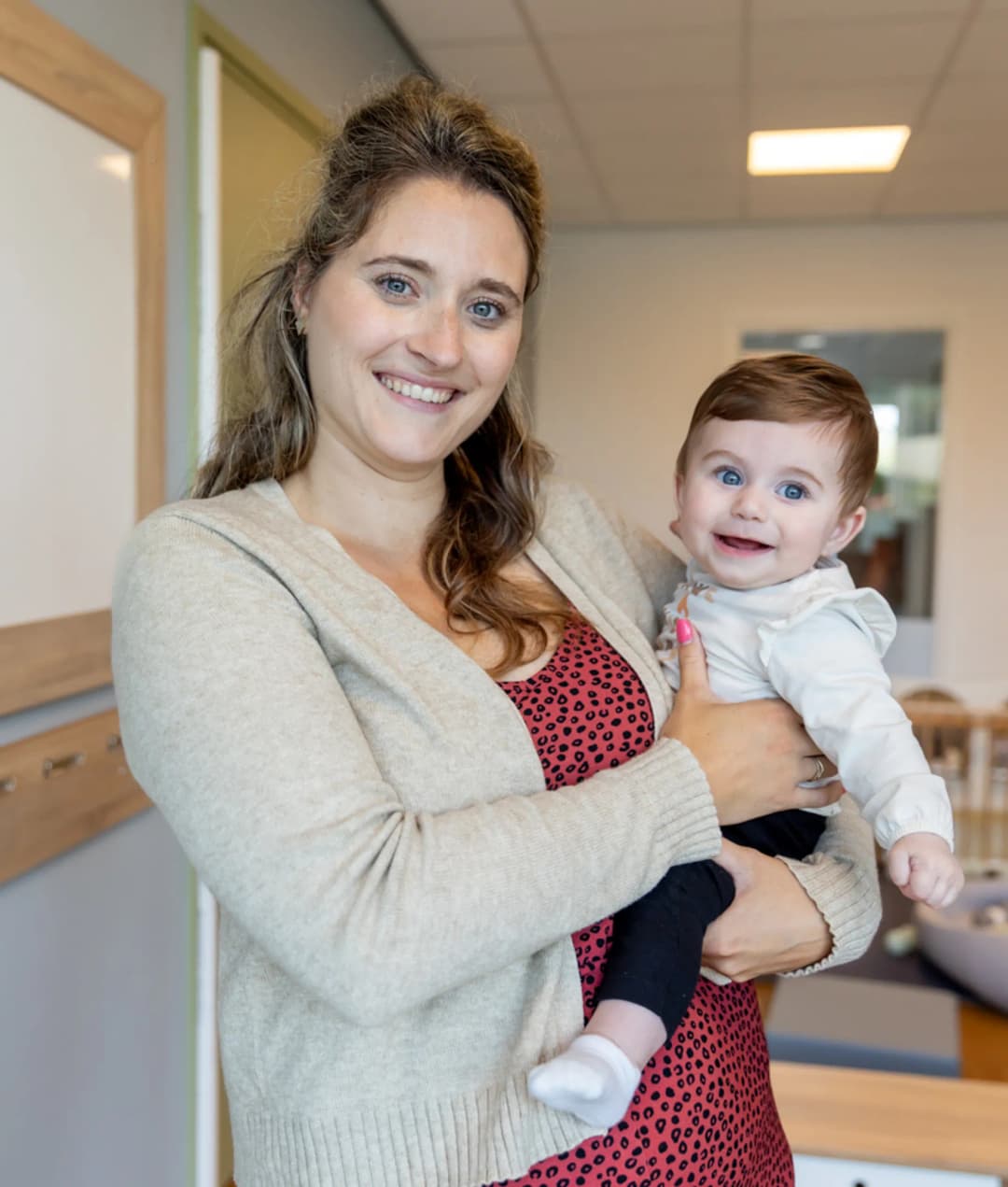 Baby wordt geknuffeld door pedagogisch medewerker bij kinderopvang Kind&co ludens