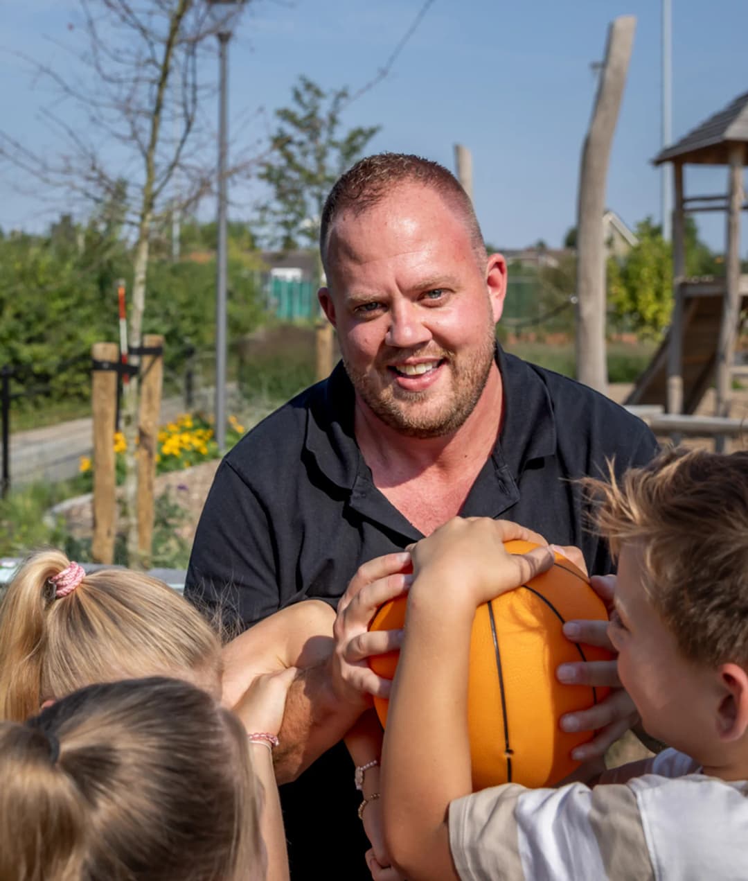 Kinderen spelen buiten met pedagogisch medewerker bij kinderopvang Kind&co ludens